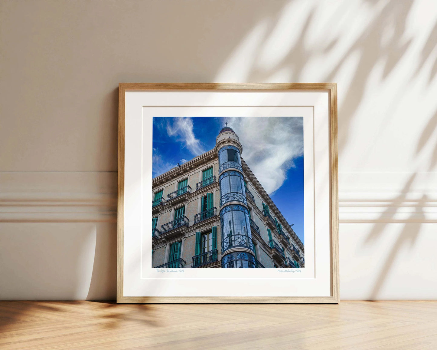 Ein Eckhaus in Barcelona, das Casas Torre Andreu. Grüne Fensterläden und ein runder, blau verglaster Eckturm vor blauem Himmel mit Wolken.