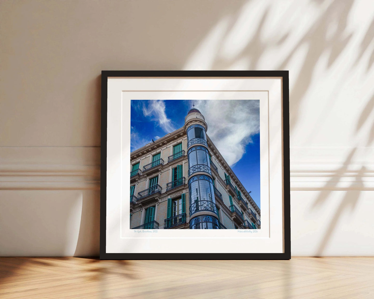 Ein Eckhaus in Barcelona, das Casas Torre Andreu. Grüne Fensterläden und ein runder, blau verglaster Eckturm vor blauem Himmel mit Wolken.