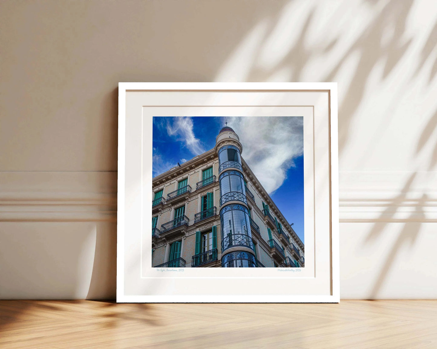 Ein Eckhaus in Barcelona, das Casas Torre Andreu. Grüne Fensterläden und ein runder, blau verglaster Eckturm vor blauem Himmel mit Wolken.