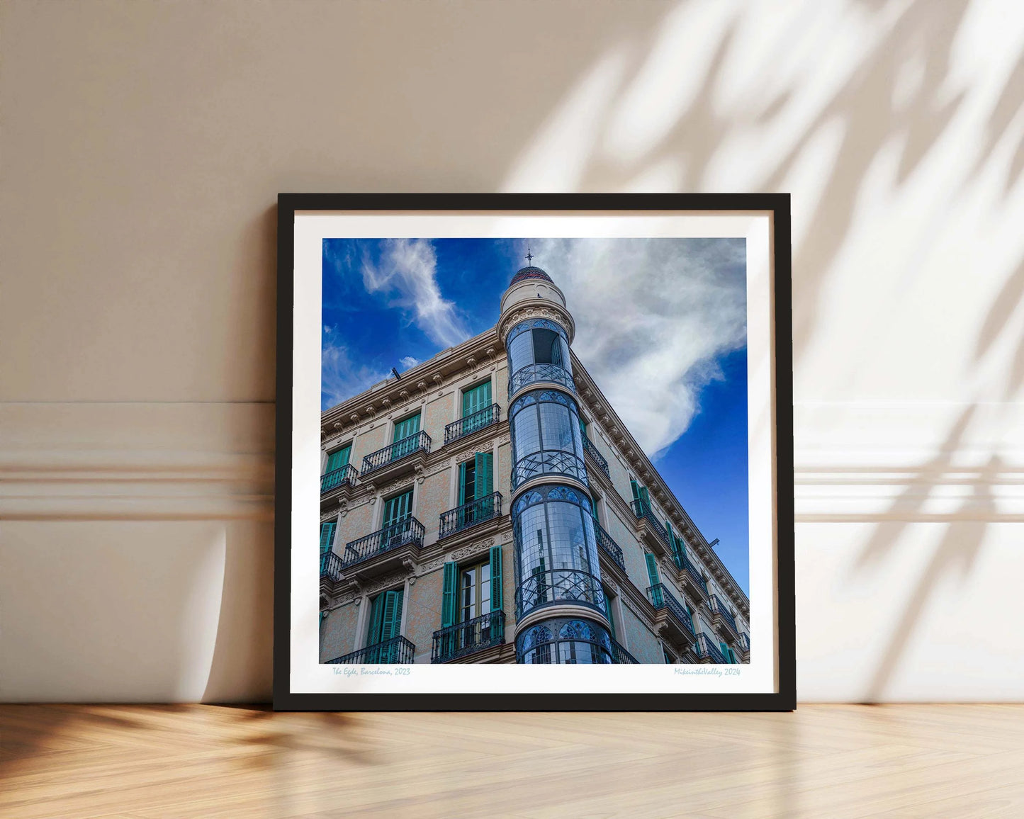 Ein Eckhaus in Barcelona, das Casas Torre Andreu. Grüne Fensterläden und ein runder, blau verglaster Eckturm vor blauem Himmel mit Wolken.