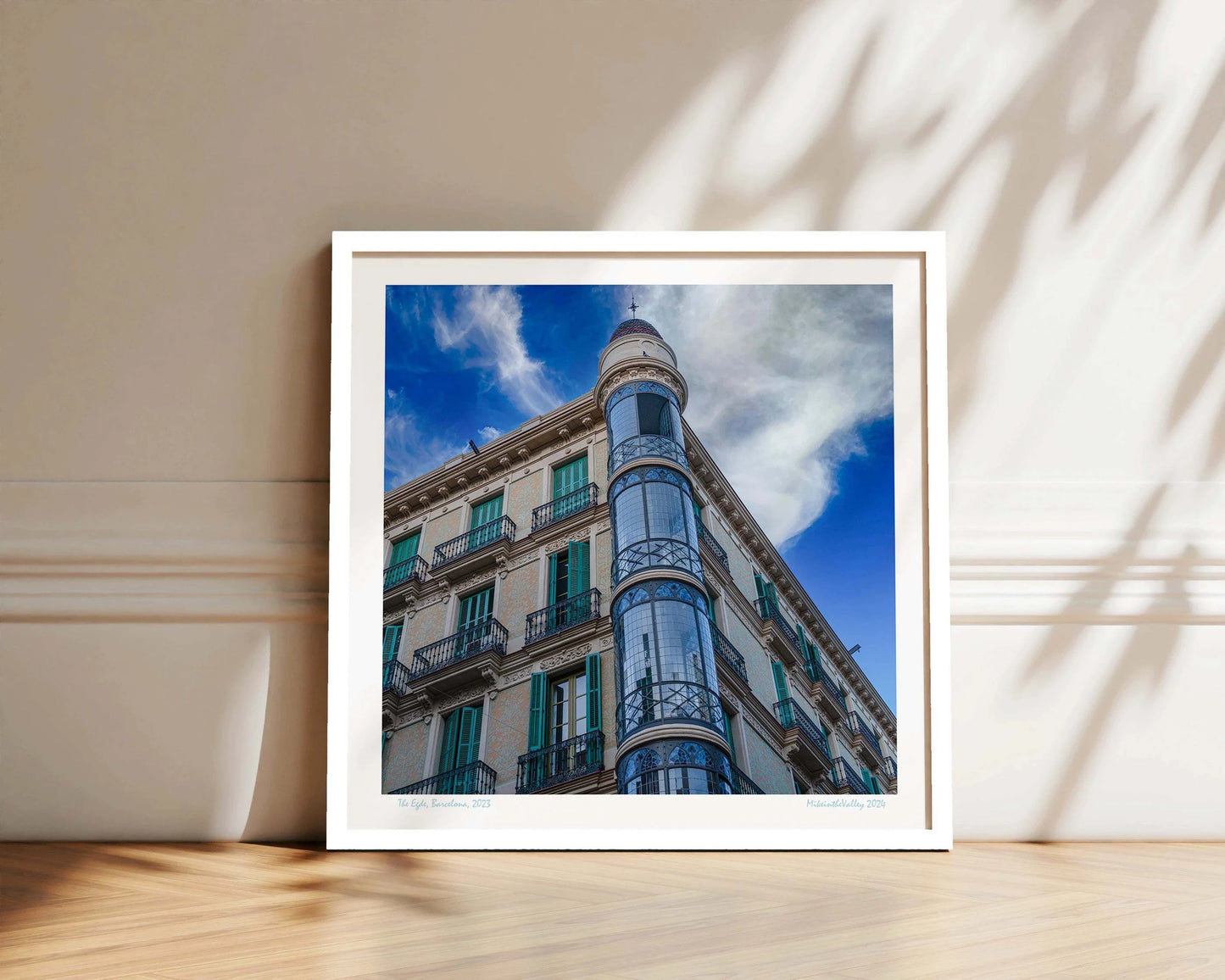 Ein Eckhaus in Barcelona, das Casas Torre Andreu. Grüne Fensterläden und ein runder, blau verglaster Eckturm vor blauem Himmel mit Wolken.