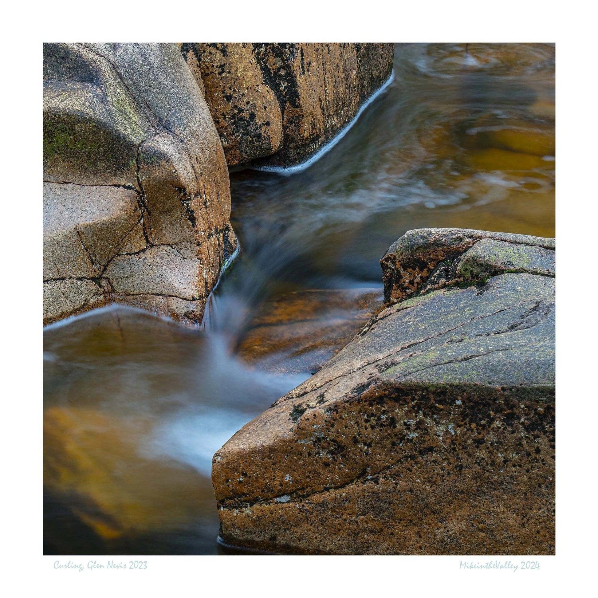 Weich dahinfließender Fluss in den schottischen Highlands, umrahmt von großen marmorierten Felsen.