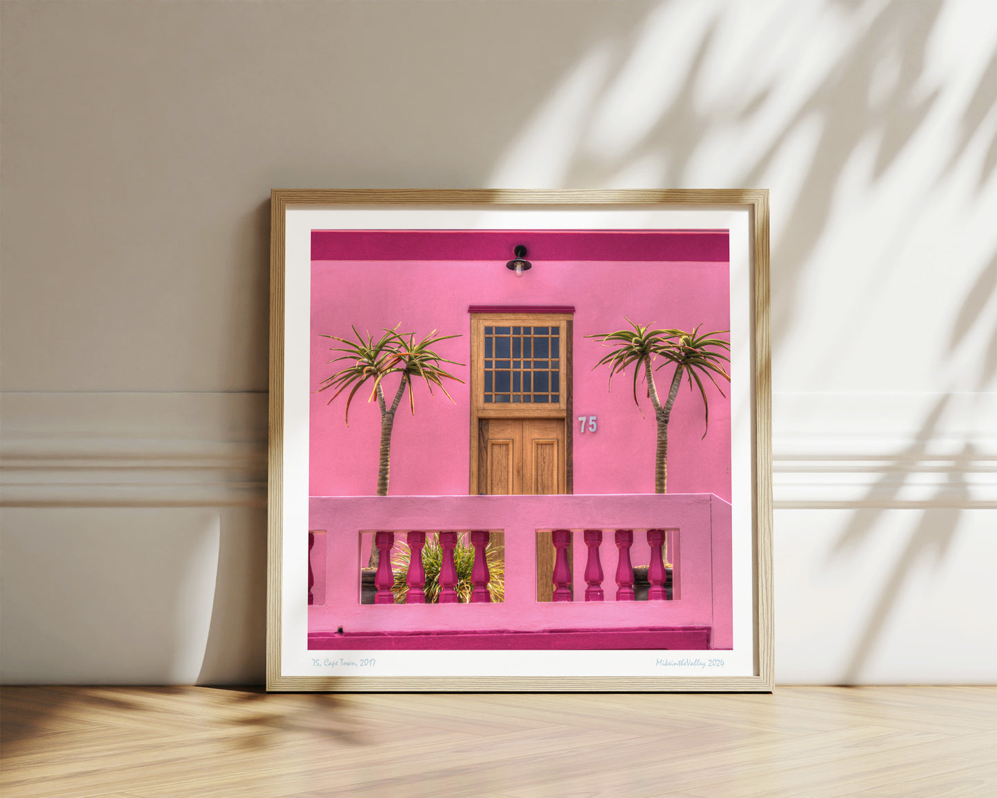 schöne Haustür aus Holz in einer pinkfarbenen Hauswand. Rechts und links davon jeweils eine Palme. Eichen-Massivholzrahmen.