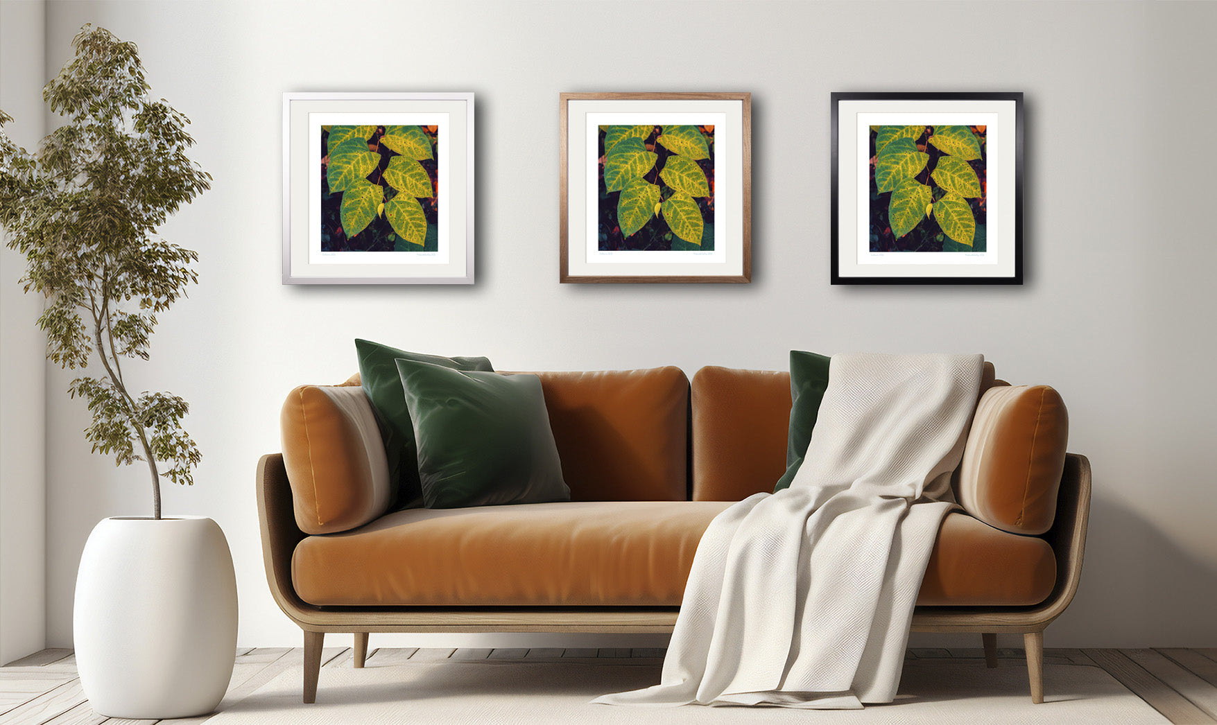 Der Kunstdruck "Six Leaves" hängt in drei verschiedenen Rahmungen über einem stilvollen Sofa